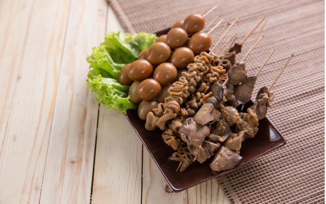 Sate usus, sate hati ampela, dan sate telur puyuh di atas piring persegi.  