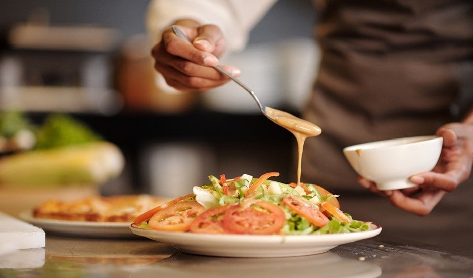 Chef sedang menuang salad dressing