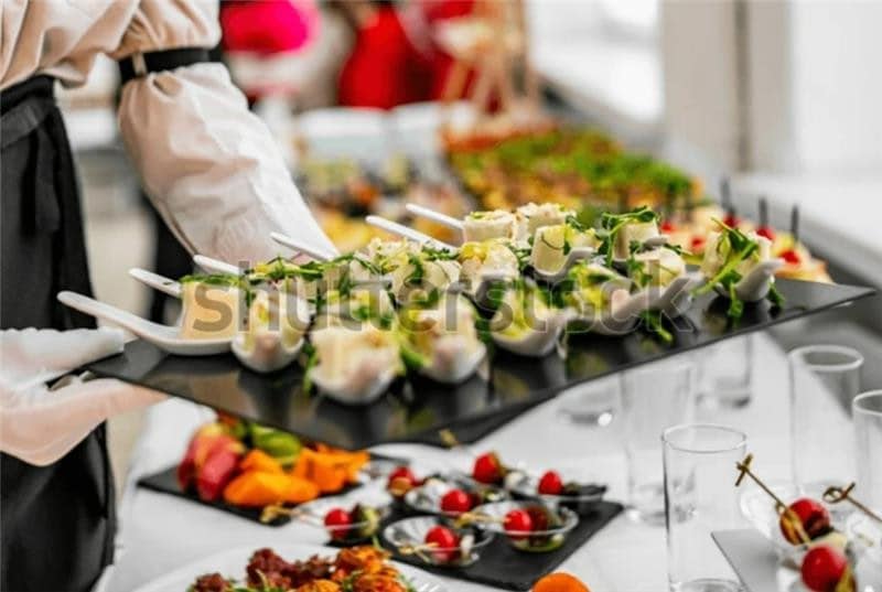 Tangan waiter sedang menata makanan di meja buffet. Tangan waiter sedang menata makanan di meja buffet.