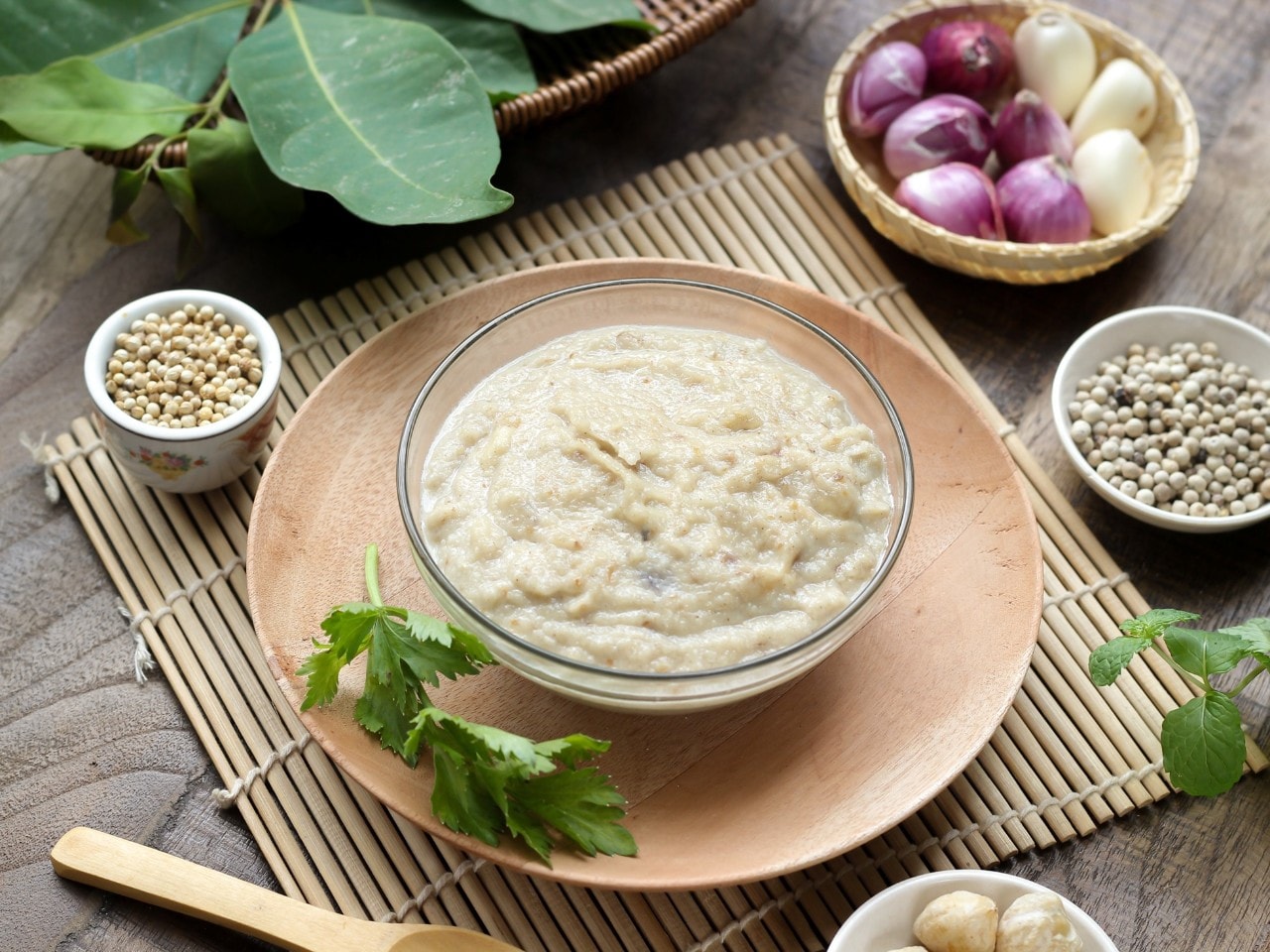 Bumbu dasar putih dikelilingi bahan-bahan segar. 