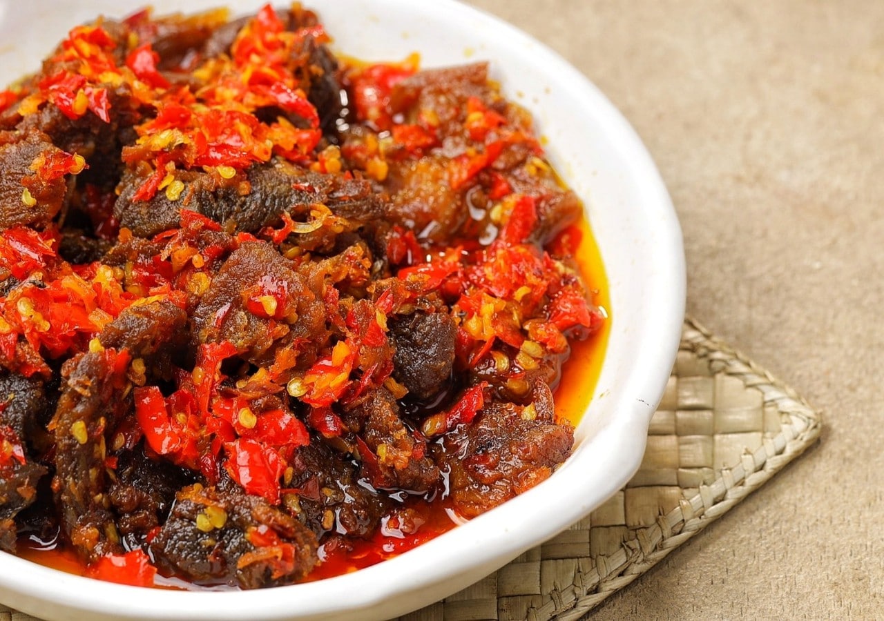 Dendeng balado khas Padang dalam piring putih. 
