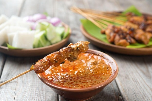 Seperti yang terlihat pada gambar, sate dicelupkan ke dalam bumbu kacang