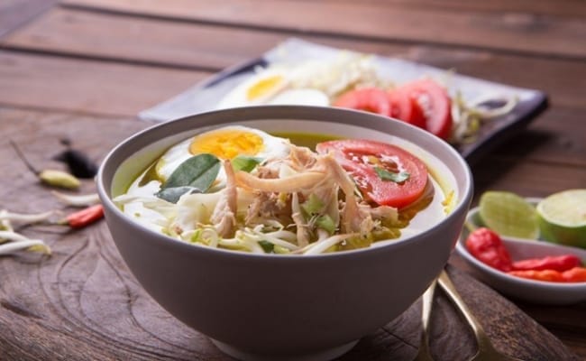 Seperti yang terlihat pada foto, ada mangkuk soto ayam kuning beserta pelengkapnya. 