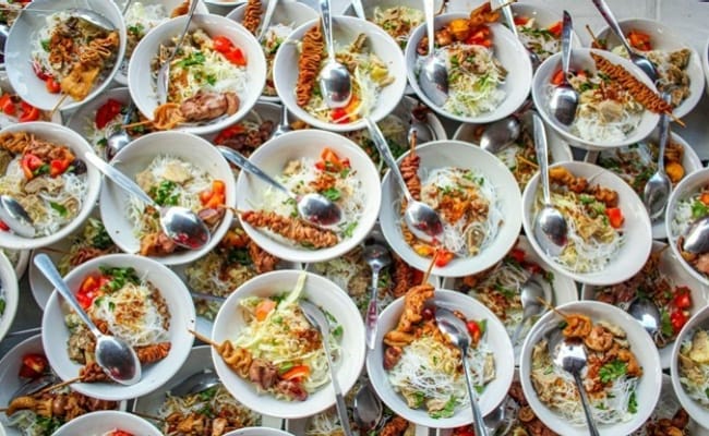 Seperti yang terlihat pada foto, ada tumpukan mangkuk dengan bahan isi soto di dalamnya.