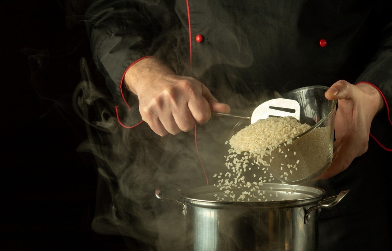 Chef sedang menuang beras ke dalam panci. 