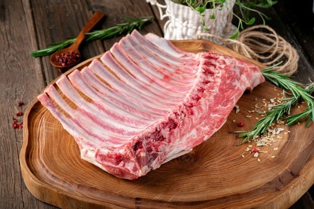 Seperti yang terlihat pada gambar, potongan iga kambing dengan herbs di atas talenan kayu