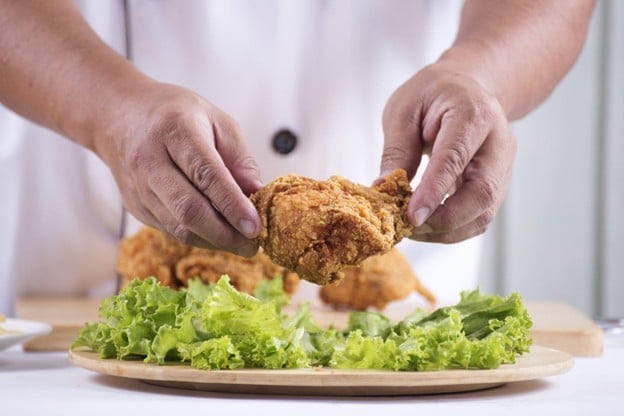 Tangan chef sedang plating ayam goreng