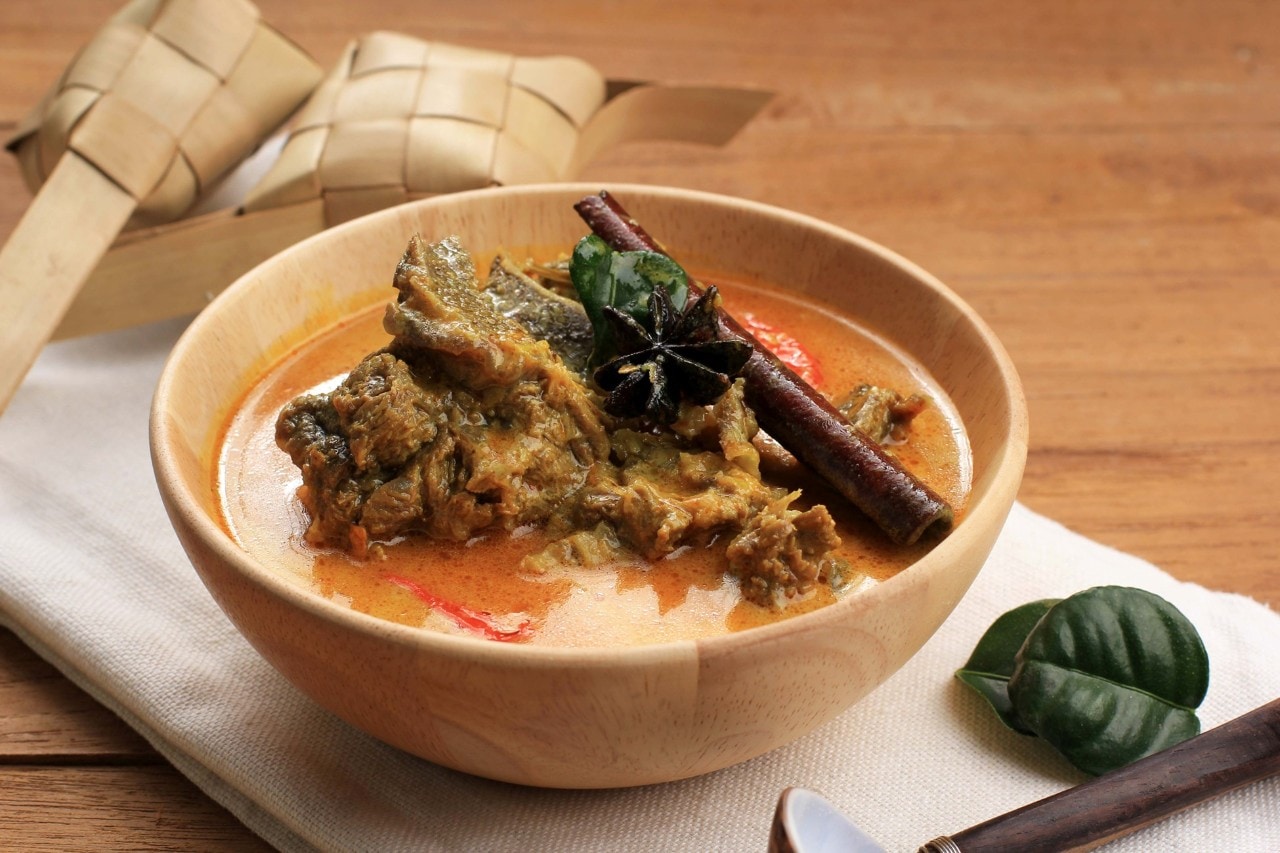 Gulai sapi dengan ketupat di belakangnya.