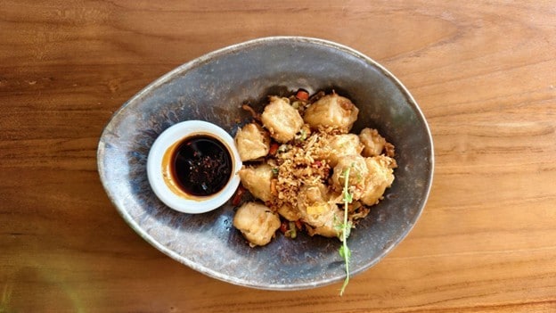 Seperti yang terlihat pada gambar, ada tahu crispy dengan hasil renyah keemasan, disajikan di piring dengan plating premium