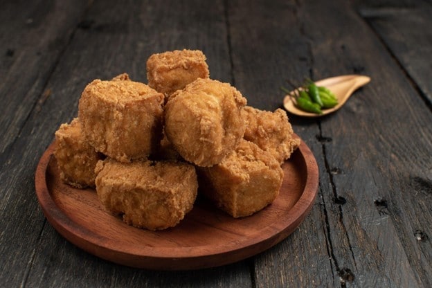 Seperti yang terlihat pada gambar, tahu crispy disajikan di atas piring kayu