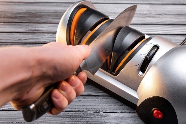 Pisau sedang diasah menggunakan electric knife sharpener. 