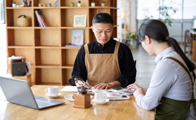 Seperti yang terlihat pada foto, wanita dan pria sedang menghitung food cost untuk bisnis restorannya