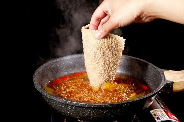 Tangan sedang memegang babat yang sudah dibersihkan. 