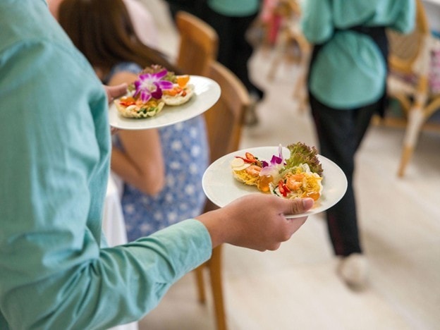 Seperti yang terlihat pada gambar, pramusaji sedang memegang dua piring hidangan