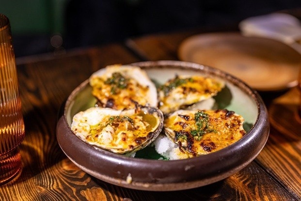 Grilled oyster di dalam piring saji bulat. 