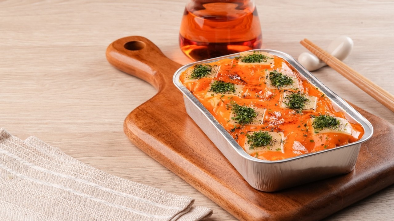 Seperti yang terlihat pada foto, ada salmon mentai rice dengan saus mentai creamy dan taburan nori di atas meja kayu.