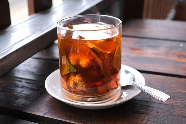 Segelas wedang dengan rempah dialasi dengan piring putih. Segelas wedang dengan rempah dialasi dengan piring putih.