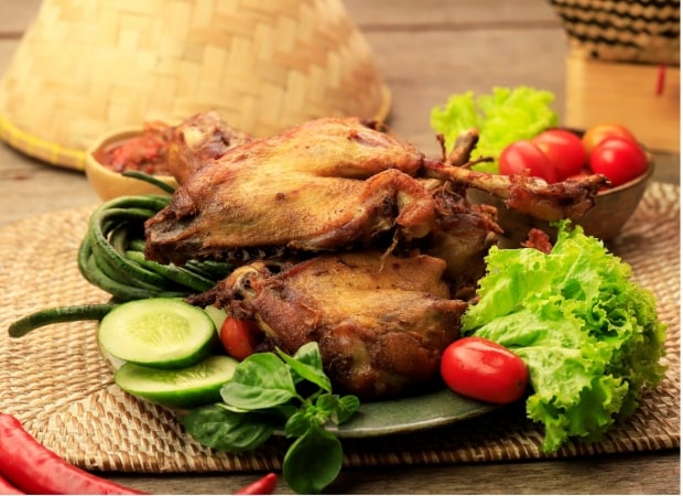 Bebek goreng dengan tomat segar dan lalapan sayuran.