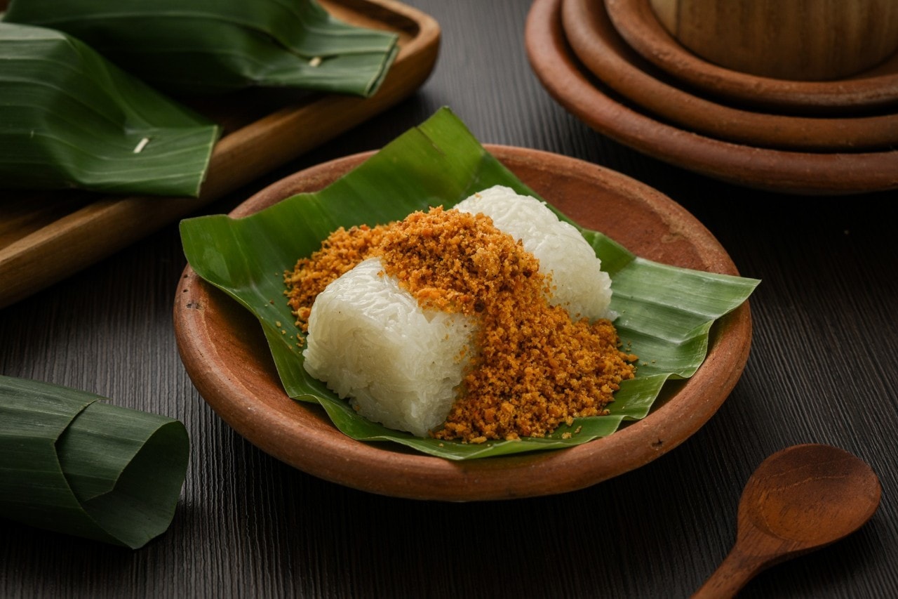 Nasi ketan ditaburi serundeng di atas piring gerabah