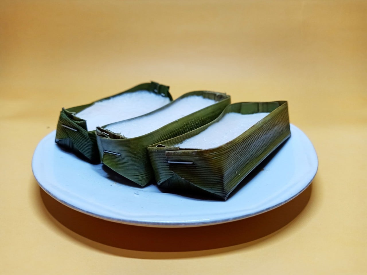 Tiga kue jojorong di atas piring putih.