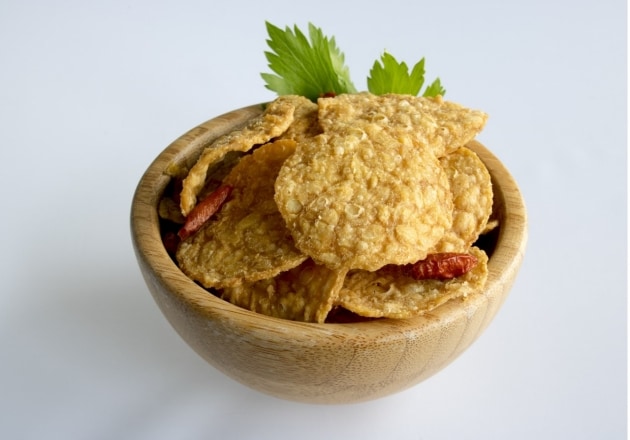 Tumpukan keripik tempe dalam mangkuk kayu.  