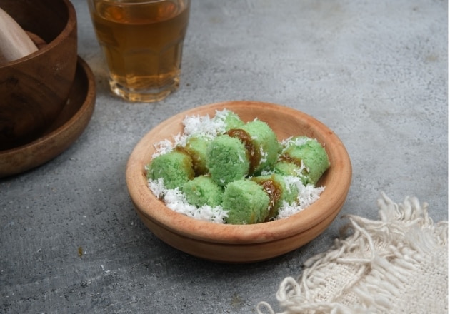 Kue putu kukus di atas wooden plate. 