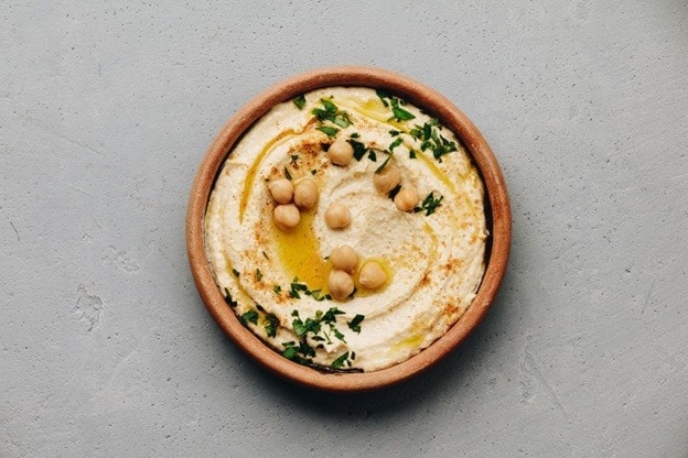 Hummus dengan taburan chickpea dan herbs dalam mangkuk tanah liat. Hummus dengan taburan chickpea dan herbs dalam mangkuk tanah liat.