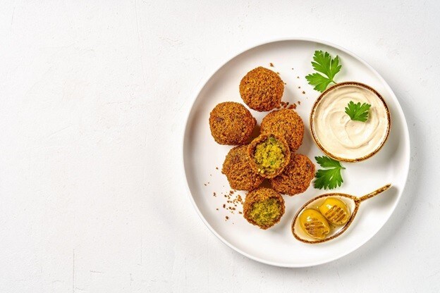 Seporsi falafel di atas piring putih dengan buah zaitun dan garlic sauce. Seporsi falafel di atas piring putih dengan buah zaitun dan garlic sauce.