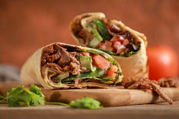 Beef shawarma di atas talenan kayu dengan daun ketumbar. Beef shawarma di atas talenan kayu dengan daun ketumbar.