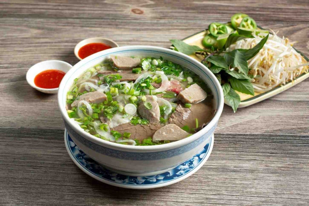 Semangkuk pho dengan sambal dan pelengkapnya.   