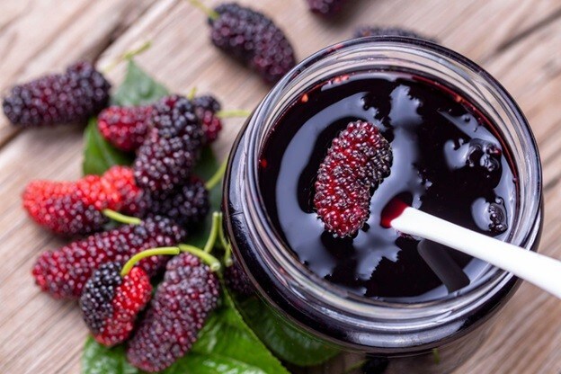 Selai mulberry dengan sendok kayu dan buah mulberry segar. Selai mulberry dengan sendok kayu dan buah mulberry segar.