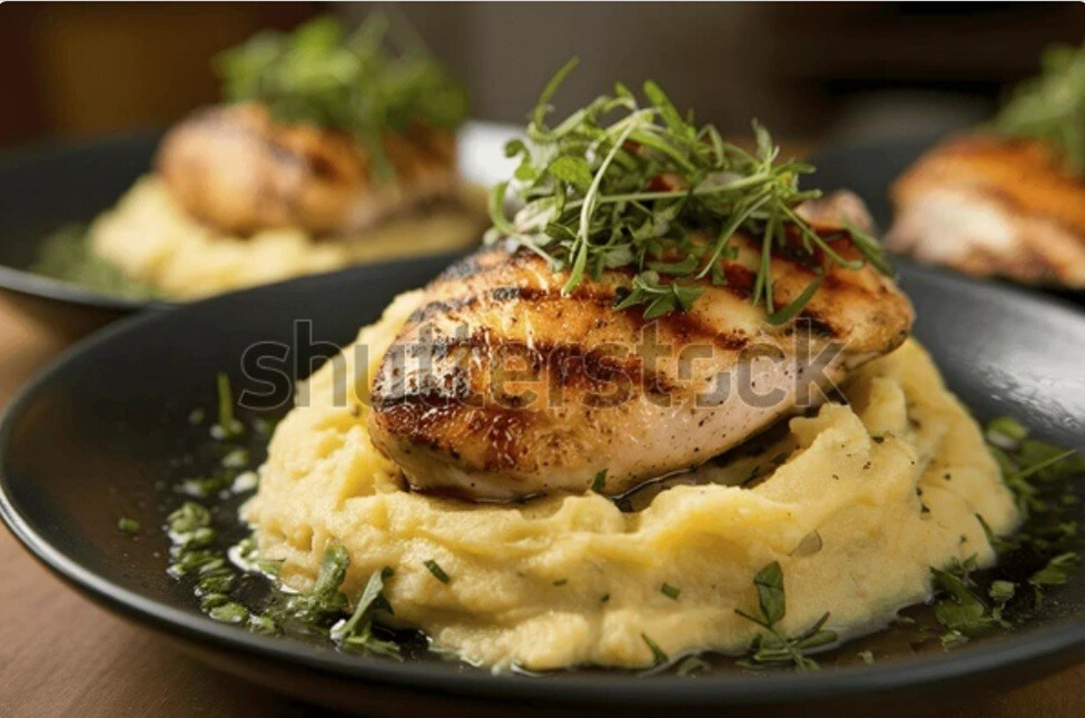 Dada ayam panggang ditata bersama mashed potato di atas piring saji hitam. Dada ayam panggang ditata bersama mashed potato di atas piring saji hitam.