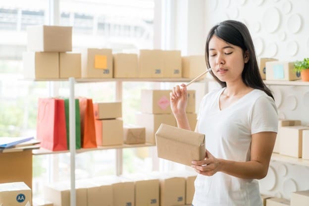 Seperti yang terlihat pada gambar, seorang wanita sedang memegang kotak kemasan