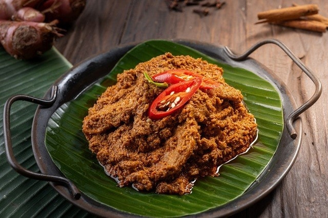 Rendang sapi dalam wadah saji beralas daun pisang. 