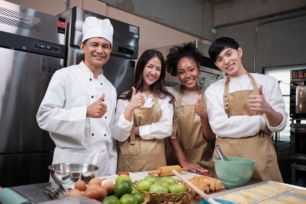 Seperti yang terlihat pada gambar, chef senior dan junior sedang tersenyum