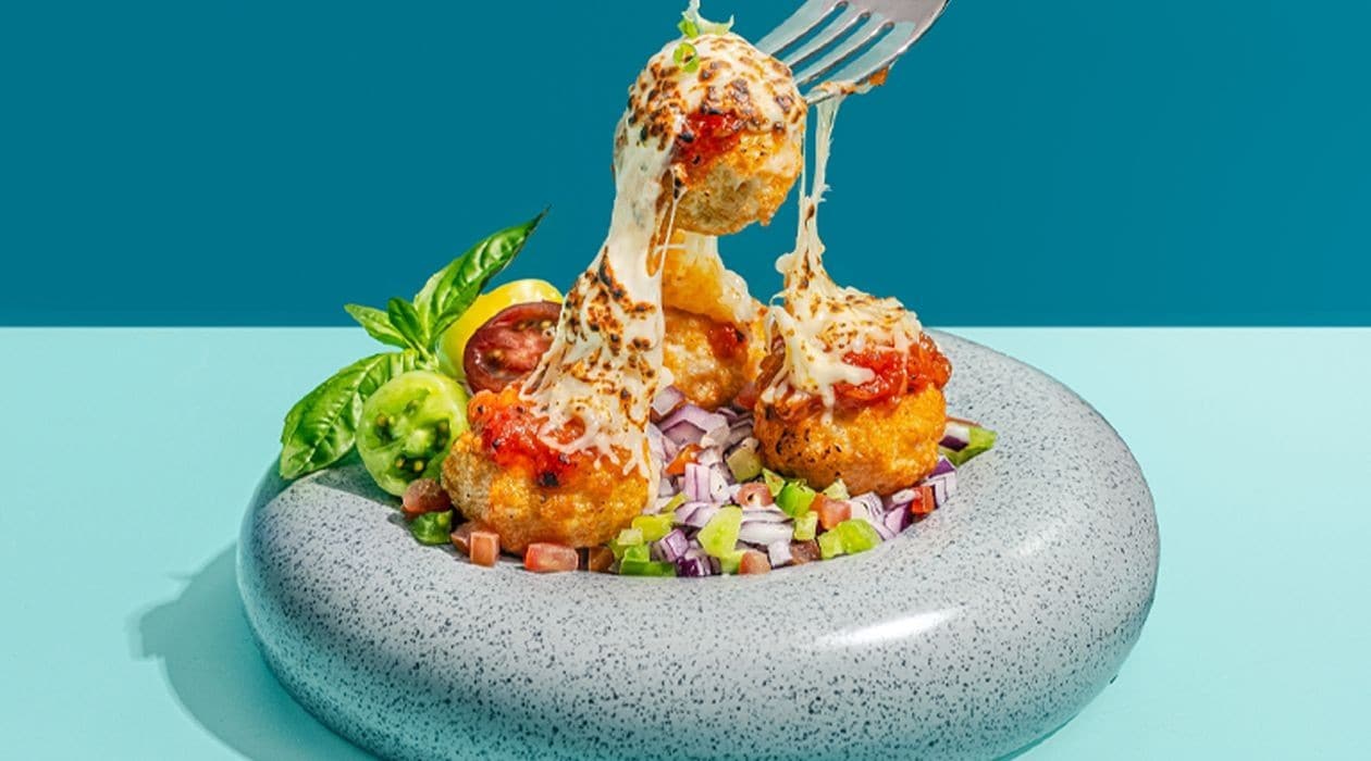 Bakso goreng dalam piring putih dengan saus di sampingnya. 