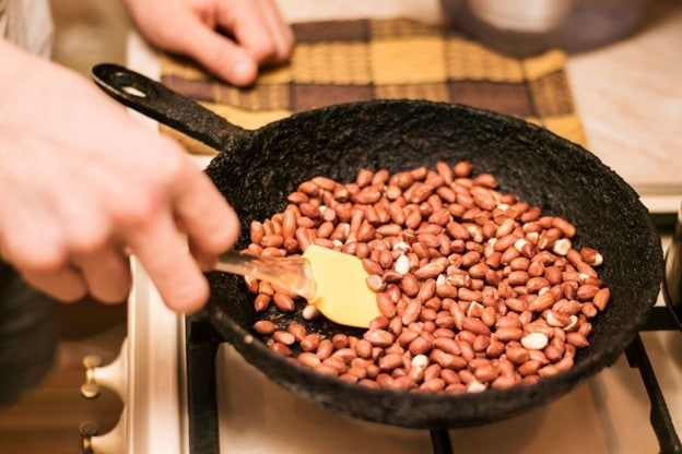 Seperti yang terlihat pada foto, kacang sedang disangrai di dalam pan.