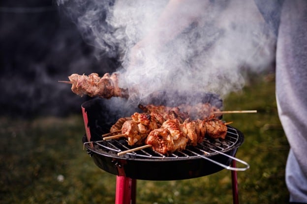 Seperti yang terlihat pada foto, ada chef sedang memanggang sate dengan teknik dry heat cooking.