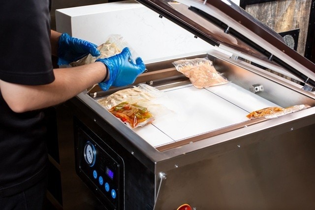 Chef sedang menggunakan vacuum sealer