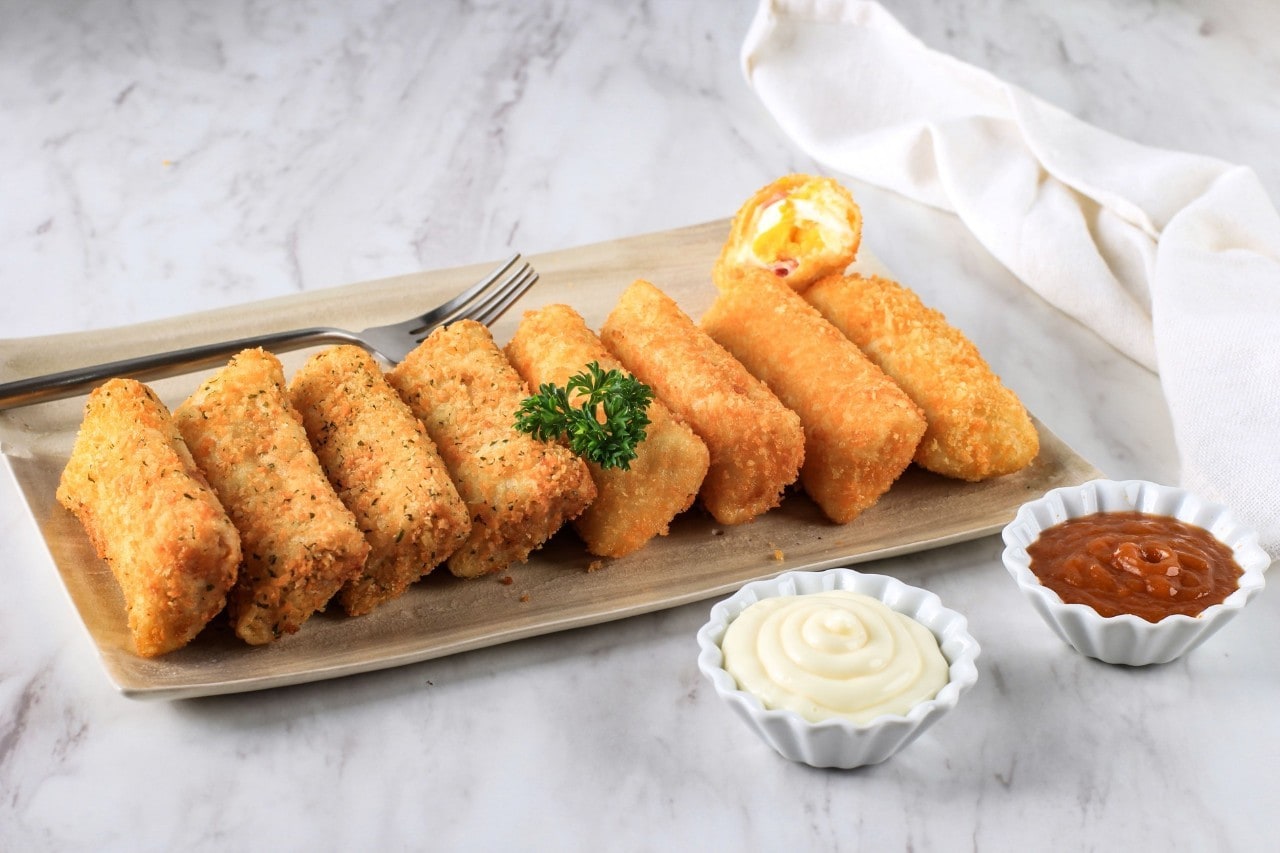 Risoles di atas piring saji kotak dengan mayones dan saus.