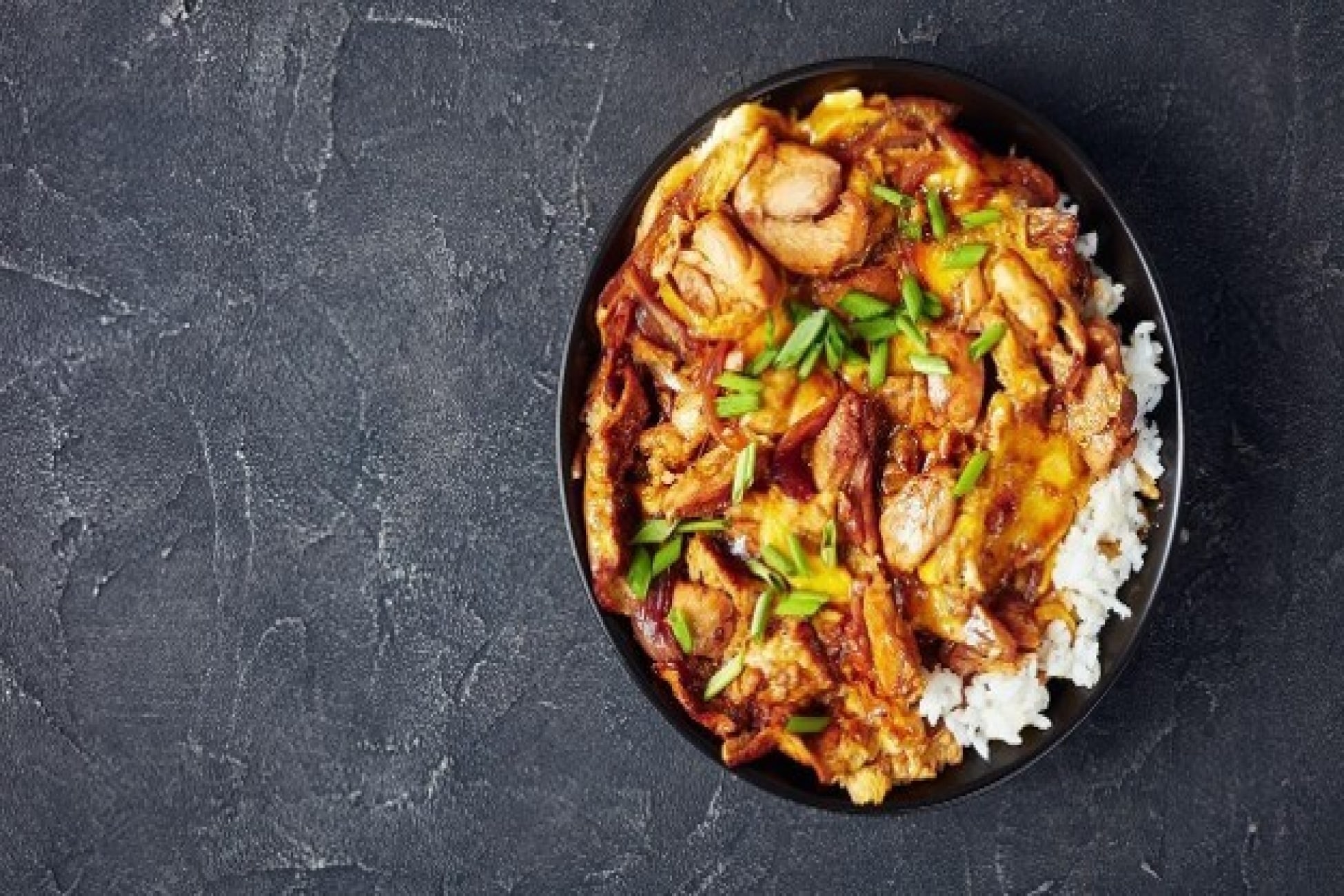 Rice bowl berisi nasi putih dan ayam berbumbu dengan taburan daun bawang.