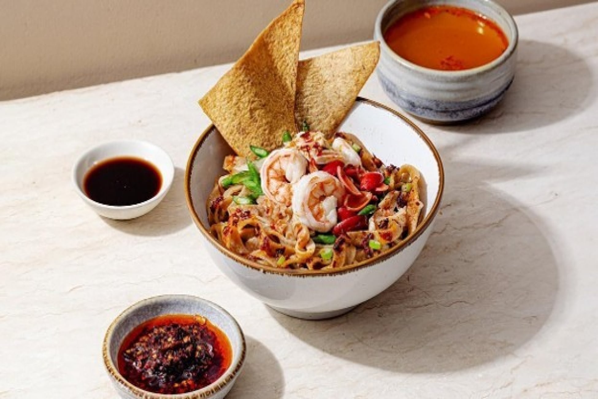 Mi dengan udang dan sayuran disajikan bersama chili oil, kecap, dan pangsit goreng.