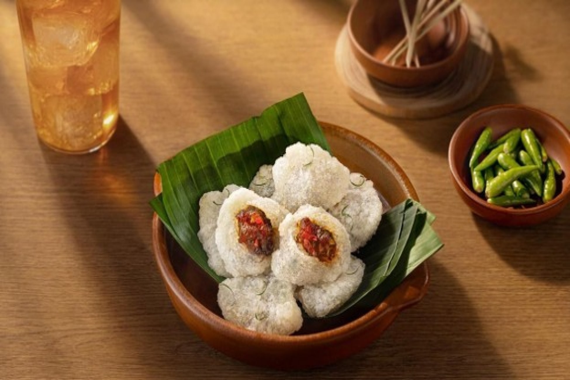 Cireng isi sambal disajikan di atas daun pisang dengan cabai hijau sebagai pelengkap.